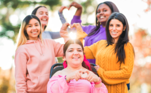 Diverse young women wearing bright colours make heart shapes with their hands
